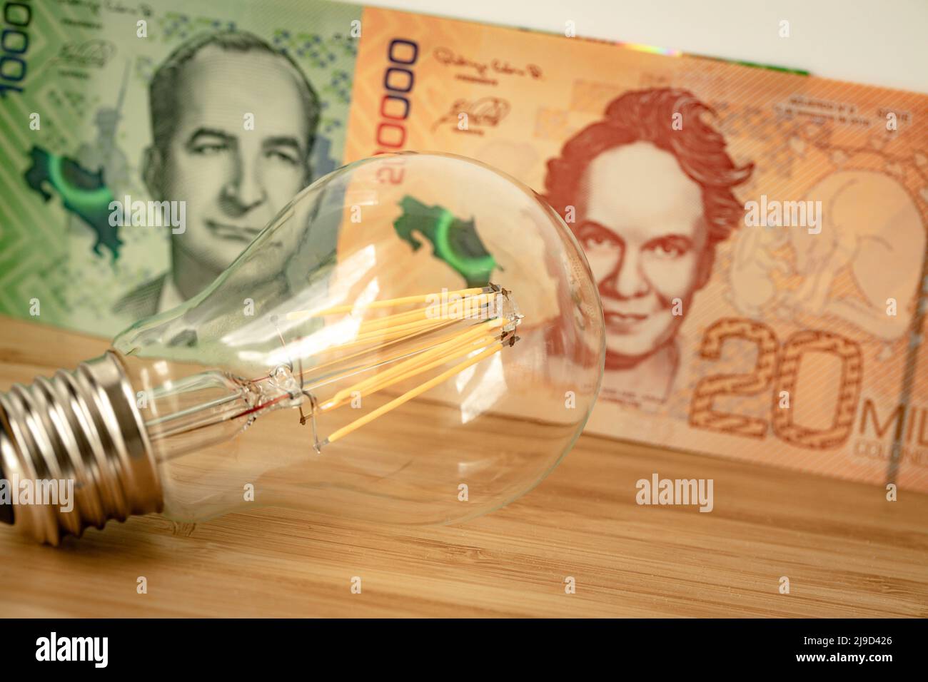 Costa Rican money and light bulb, Concept of rising energy and electricity prices in Costa Rica