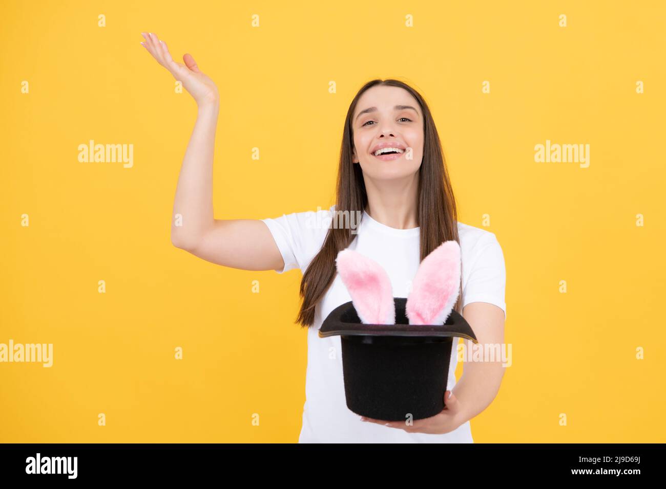 Happy woman in easter bunny ears. Rabbit ears appear from the magic hat. Stock Photo