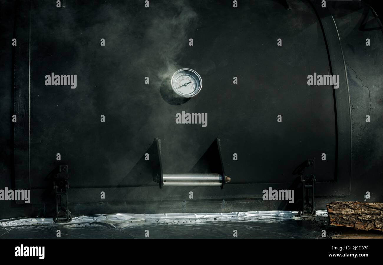 Smoke coming out of a smokestack of big black smoker grill or barbecue