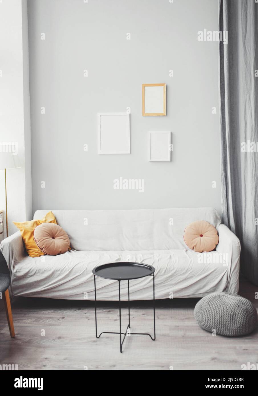 Stylish interior of living room with sofa, design furniture, pillow and elegant accessories. Modern home decor. Mock up poster frame. Template. Stock Photo