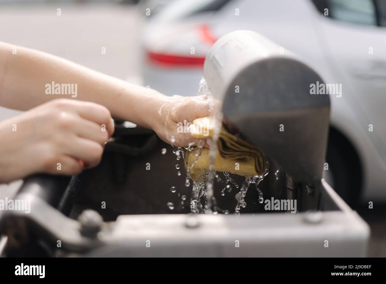 Female wash rug in water. Closeup woman's hand in front of car on self servise car wash. Squeez
