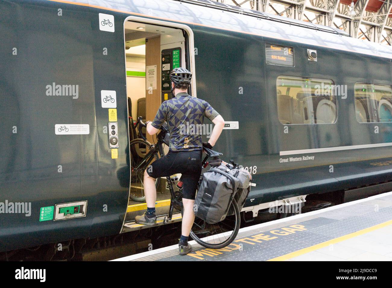 Cyclist carrying his bike onto GWR train at London Paddington railway