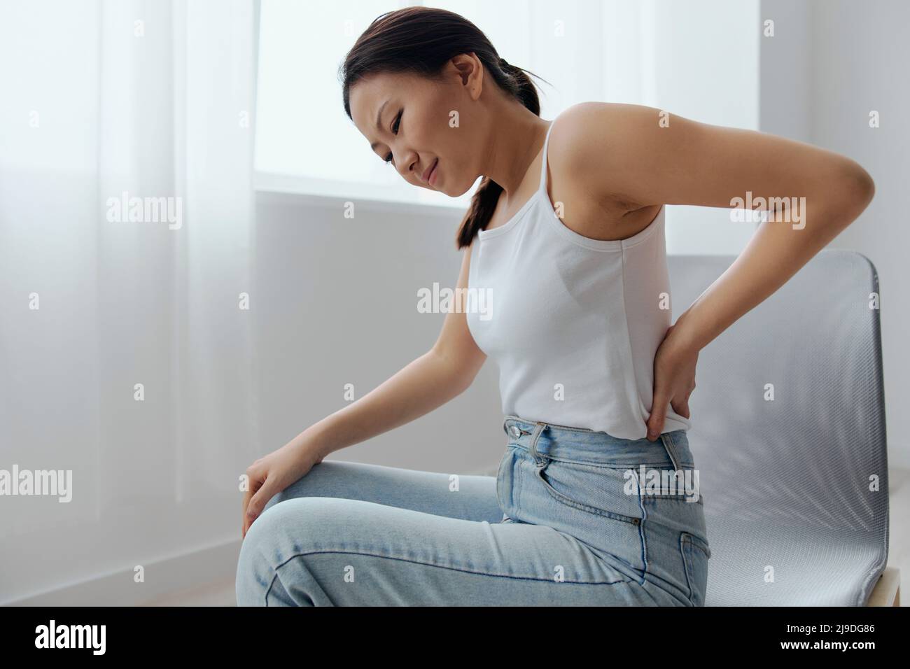 Suffering from scoliosis osteochondrosis after long study pretty young  Asian woman feel hurt joint back pain laptop in incorrect posture sit on  chair Stock Photo - Alamy