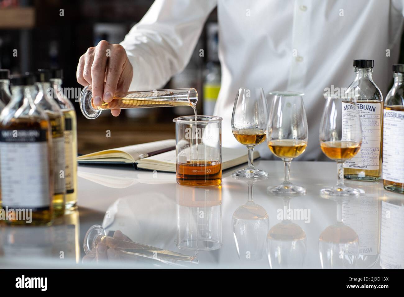 Single malt whisky blending . Whisky blender taking note Stock Photo