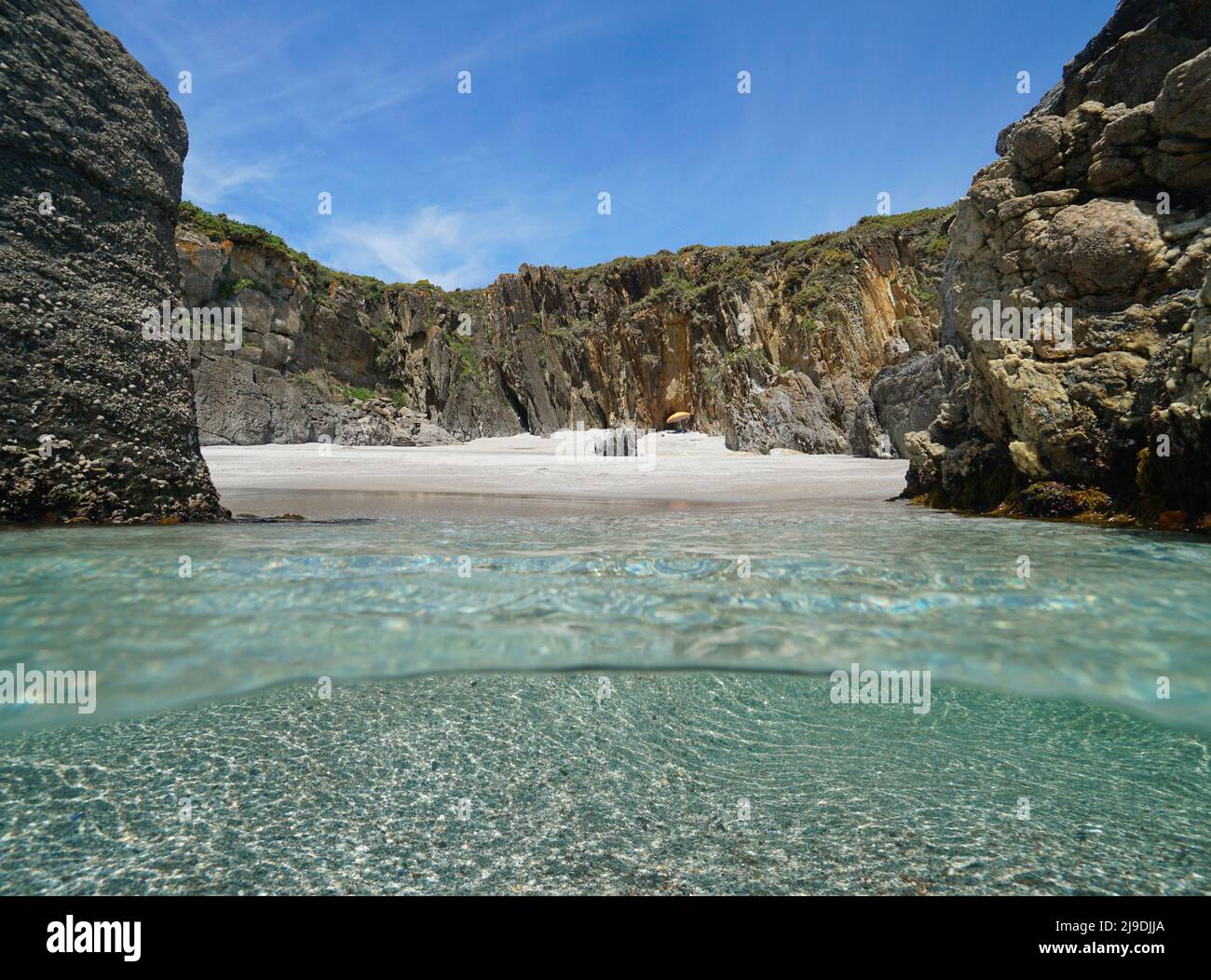 Secluded beach sea shore with sand and rocks, Atlantic ocean, Spain, Galicia, Rias Baixas, split level view over and under water surface Stock Photo