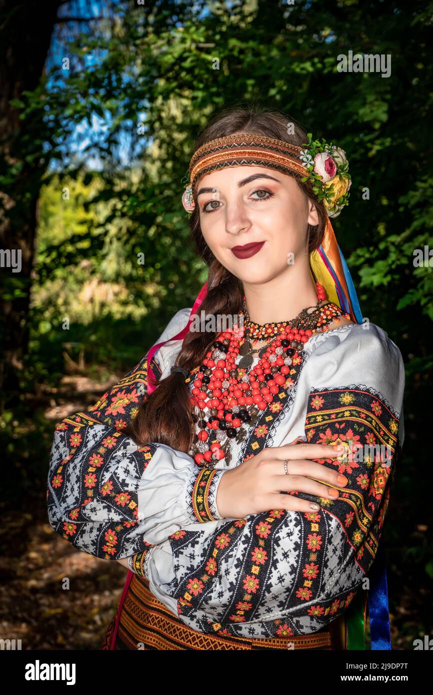 Ukrainian girl in national Ukrainian dress stands on a path in the woods Stock Photo
