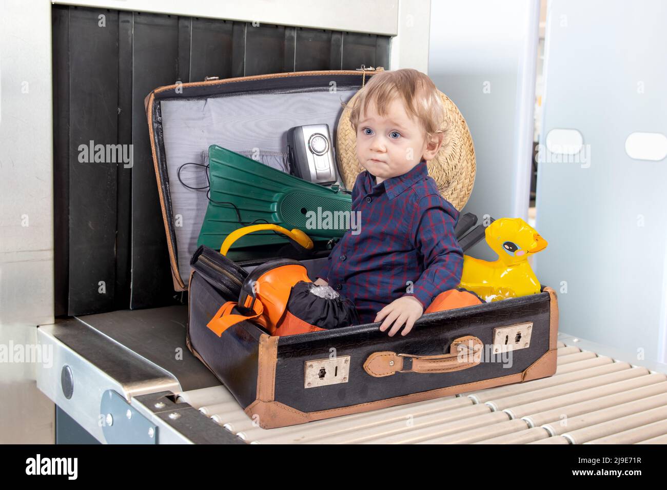 A little boy sits inside a suitcase with travel equipment, on control of luggage. Stock Photo