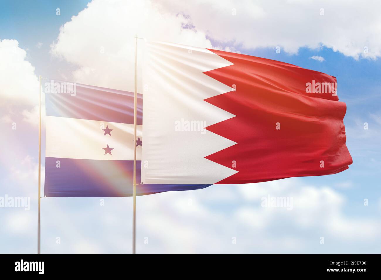 Sunny blue sky and flags of bahrain and honduras Stock Photo