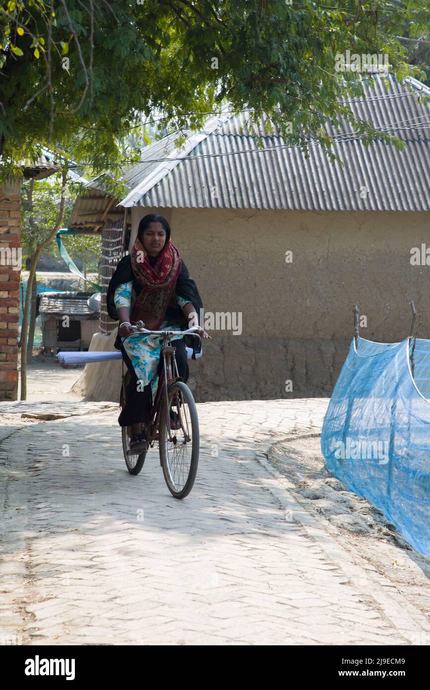 A Bangladeshi NGO worker traveling through the village by riding a bicycle in Satkhira. Riding bicycle for women social taboo in Bangladeshi society. Stock Photo