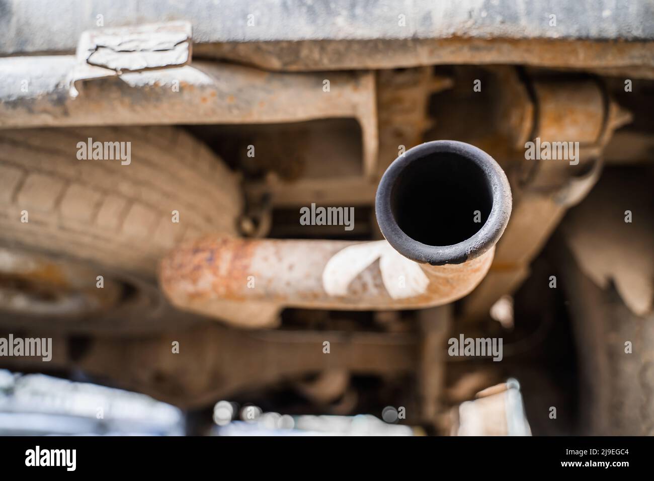 Rusty exhaust pipe with soot closeup. The spare tire is installed from