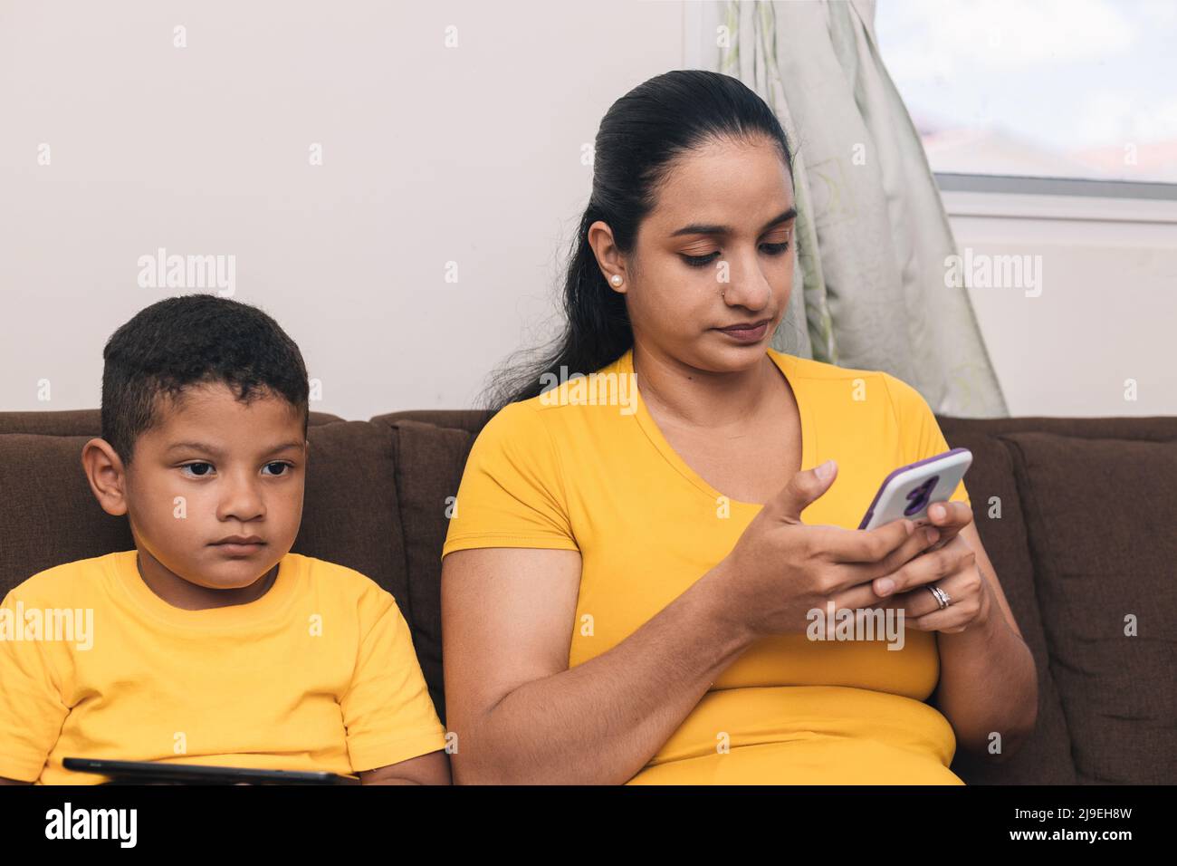 mother and son sitting in the armchair, breast looking at the cell phone Stock Photo