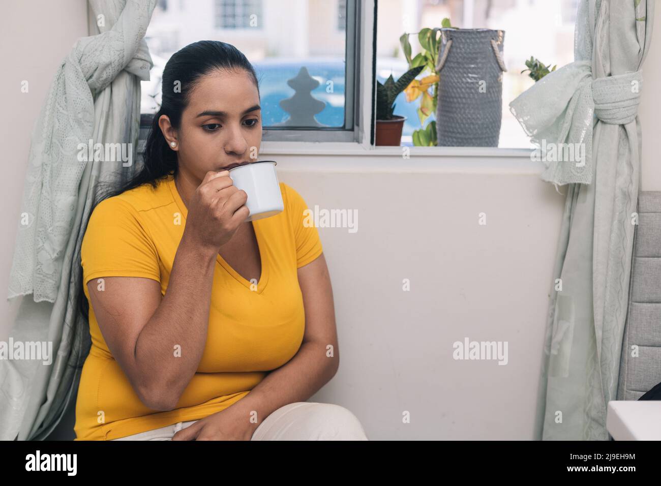 woman with yellow sweater, drinking coffee in white cup Stock Photo