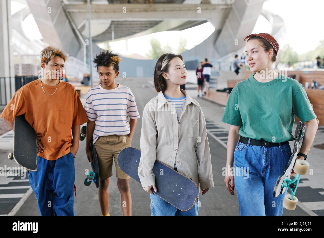 Diverse group of teenagers in skatepark outdoors at urban area wearing sporty outfits, copy space Stock Photo