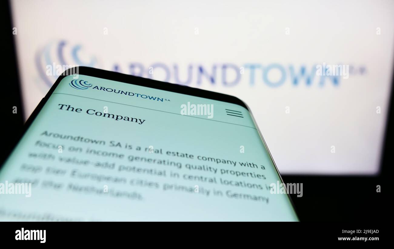 Mobile phone with website of real estate company Aroundtown SA on screen in front of business logo. Focus on top-left of phone display. Stock Photo