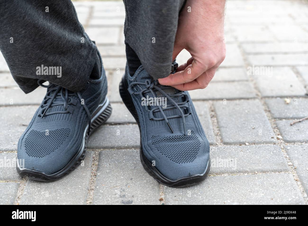 Picture of Bottom section of a mature man tying his shoelace. A man's hand tying a ...