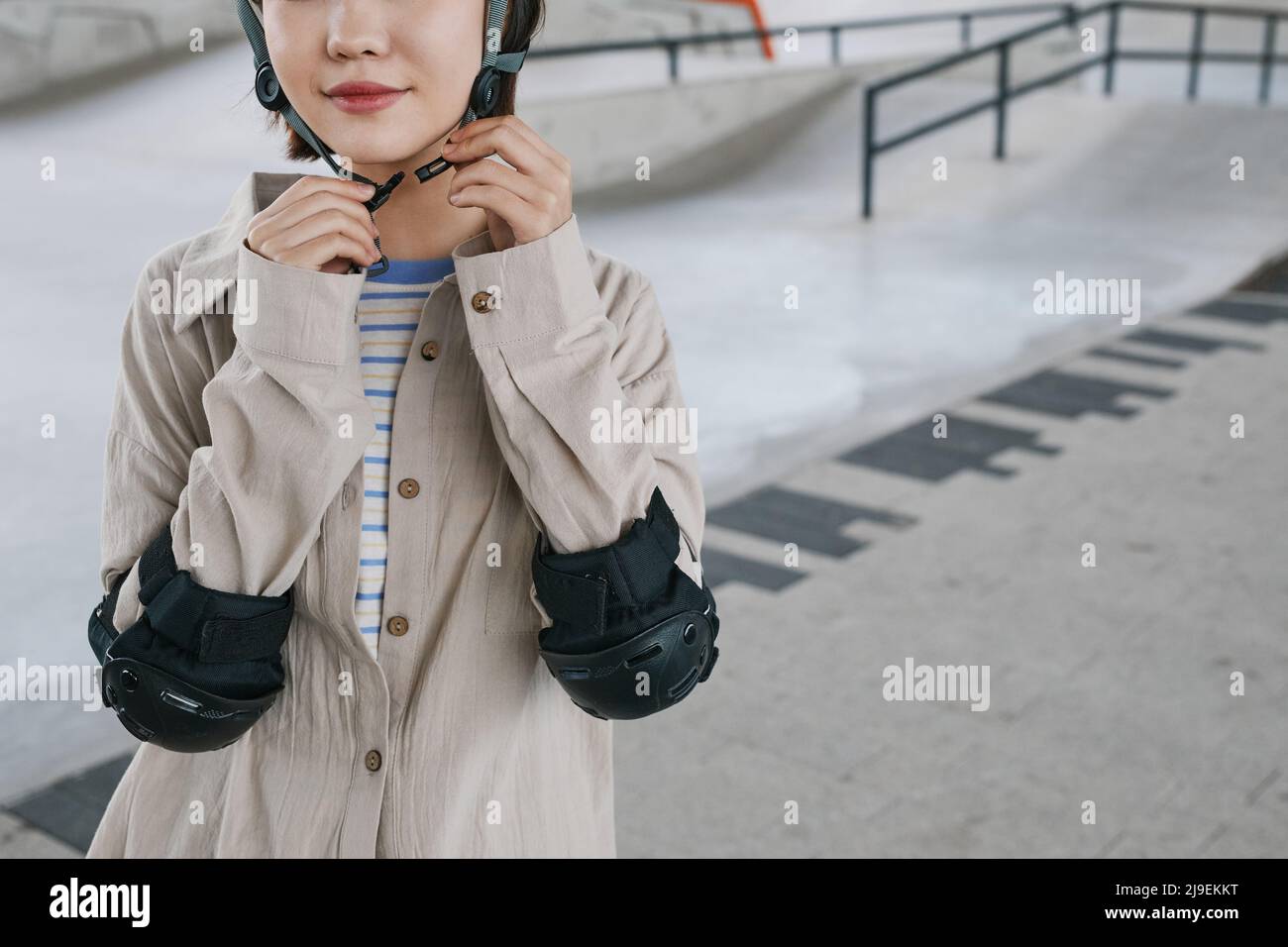 Midsection shot of young girl wearing protective guards and helmet in skatepark, copy space Stock Photo