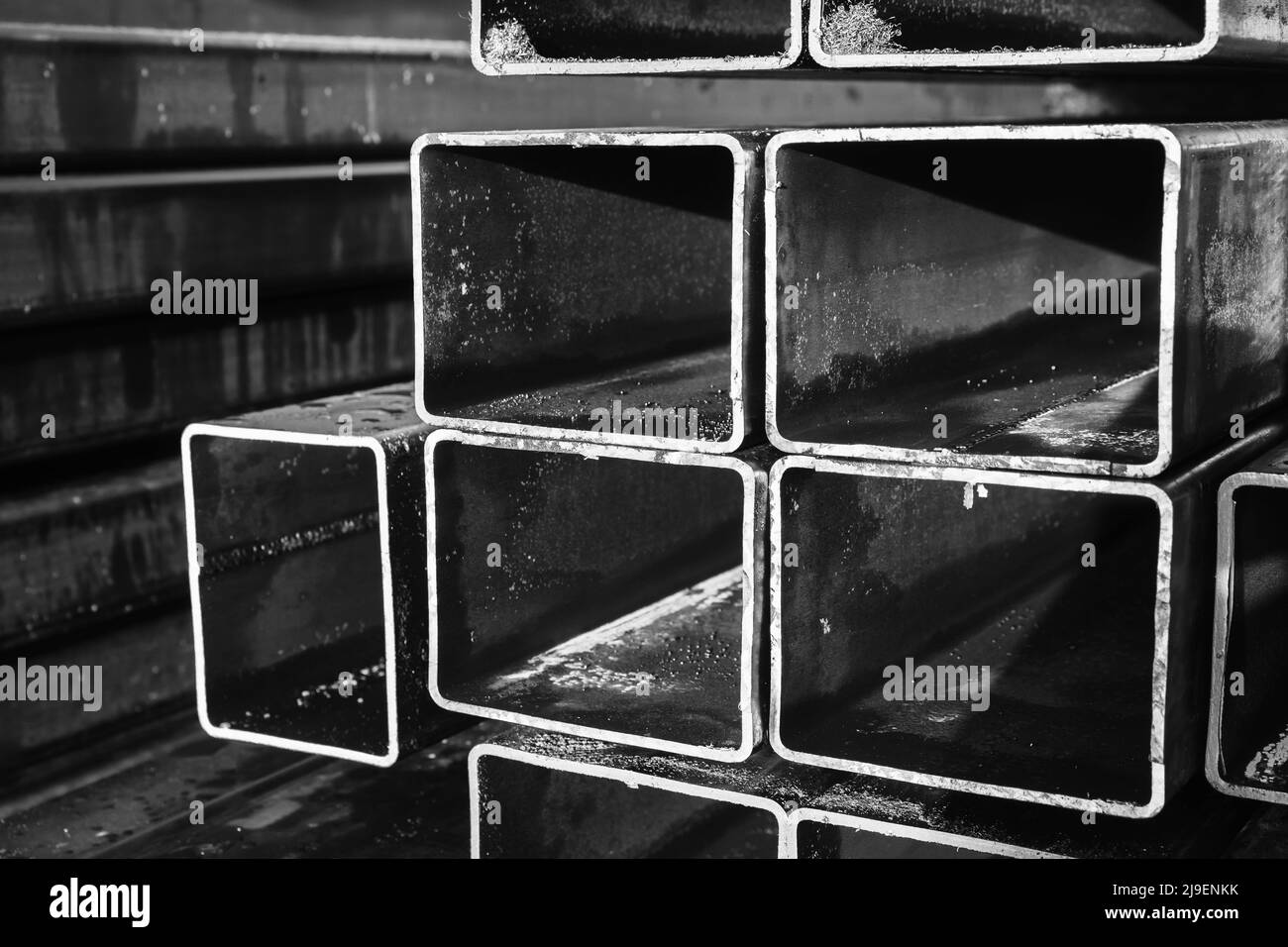 Black and white metallurgy background, stacked rolled metal products, steel pipes with rectangular cross-section Stock Photo