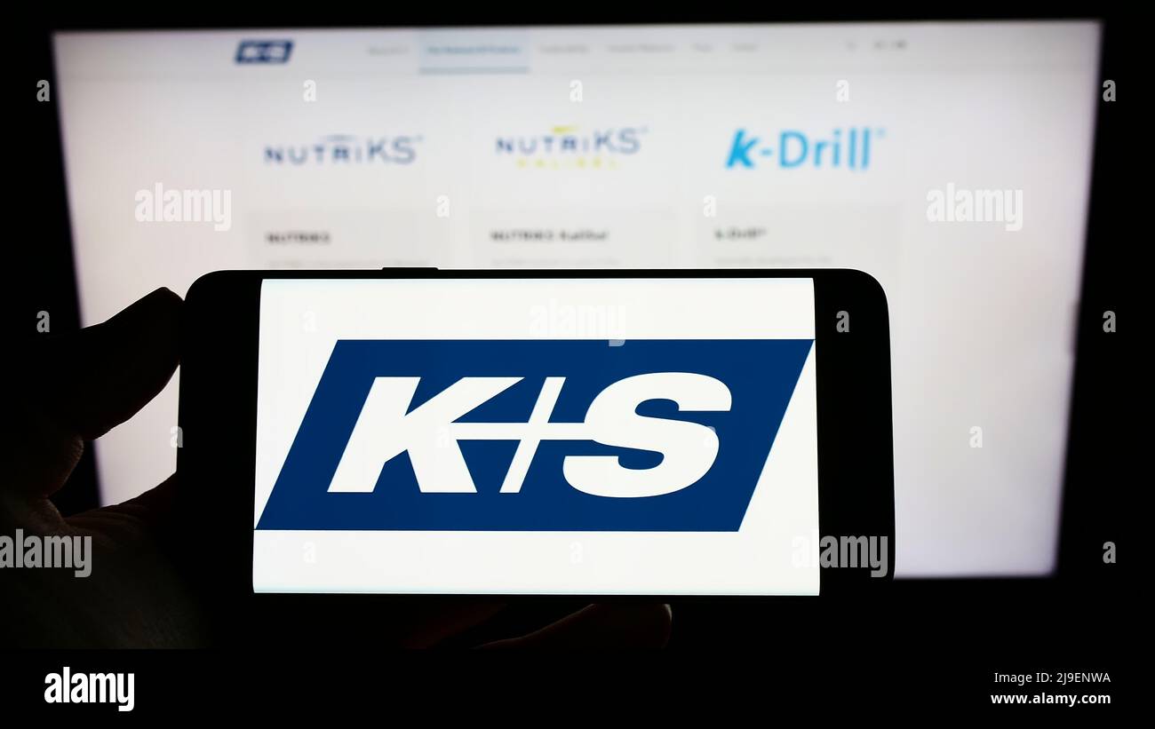 Person holding smartphone with logo of German mining company KS AG (K plus S) on screen in front of website. Focus on phone display. Stock Photo