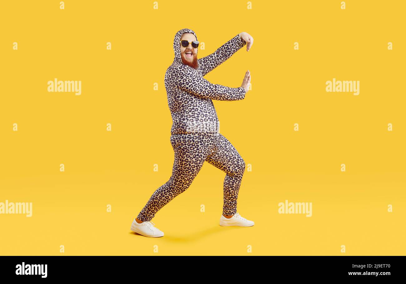 Funny cheerful fat guy wearing crazy leopard PJs dancing and having fun in fashion studio Stock Photo