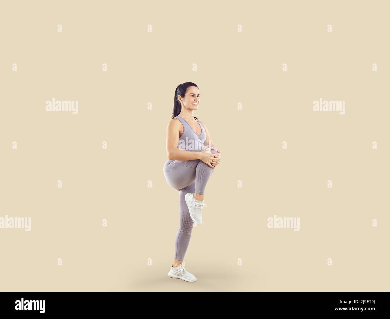 Happy fit woman in sportswear doing high knee exercise during her ...