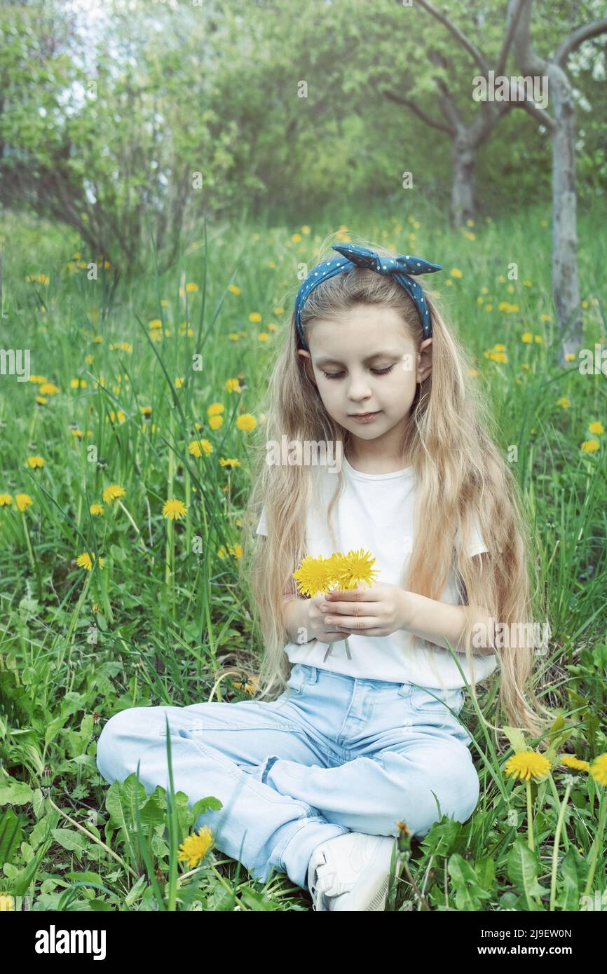Image of pretty little girl sitting on dandelions field, happy cheerful ...