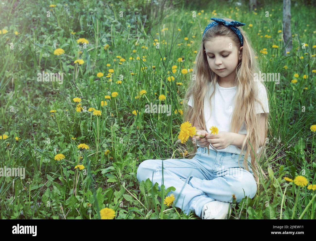 Image of pretty little girl sitting on dandelions field, happy cheerful ...