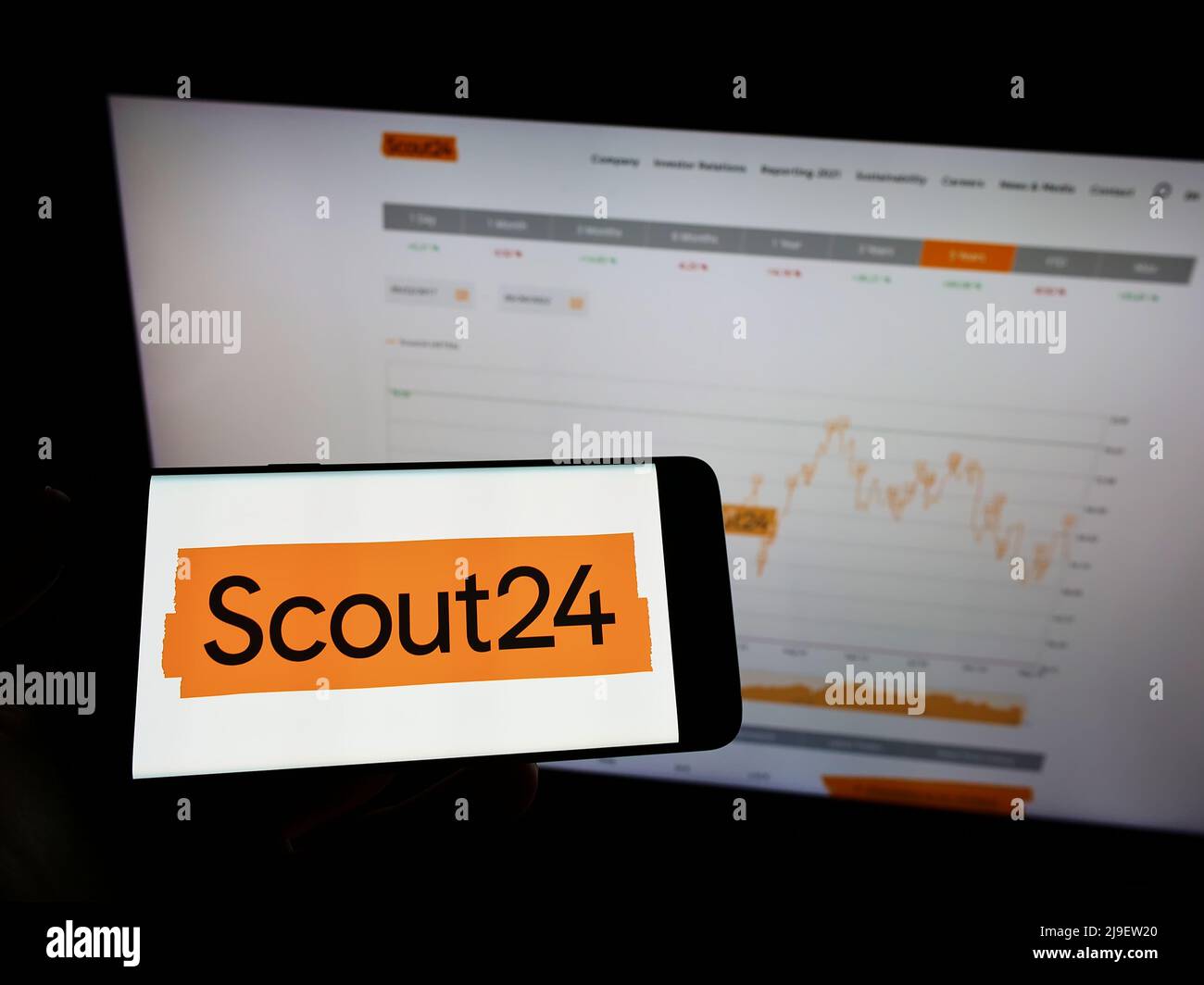 Person holding mobile phone with logo of German real estate platform company Scout24 SE on