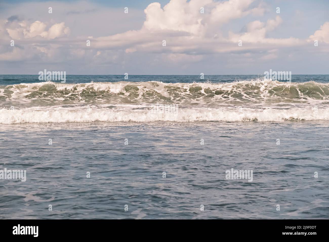 Ocean waves. Big surfing waves breaking onto beach at Bali, Indonesia. Scenic view of high emerald waves with white foam moving towards the shore on a Stock Photo