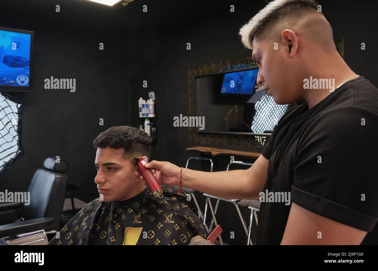 Young man in barbershop cutting hair in dark vintage business Stock Photo
