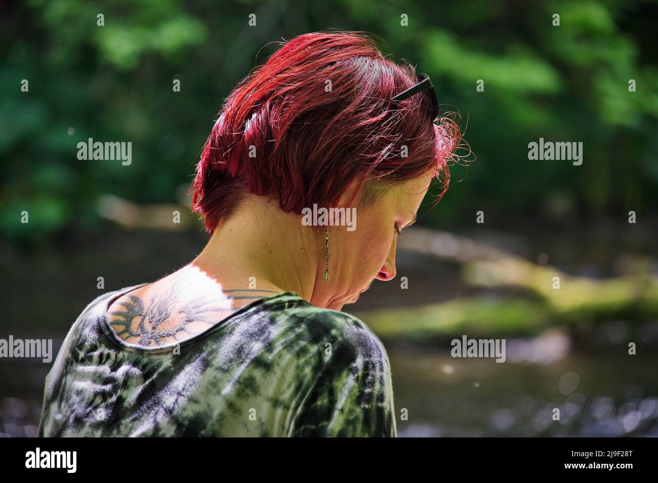 Portrait of red hair mature woman sitting in forest Stock Photo