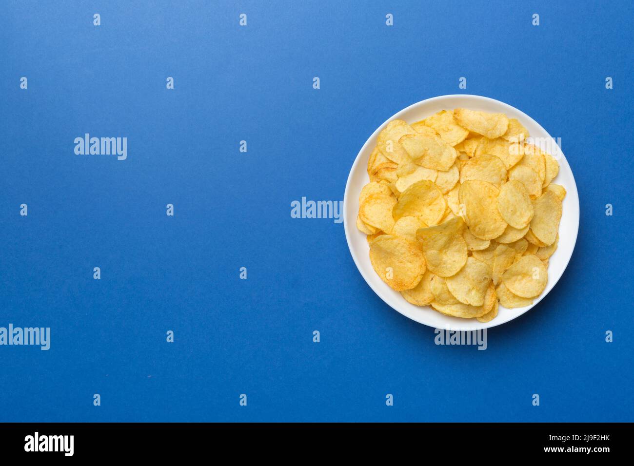 Potato chips on bowl isolated on colored background. Delicious crispy