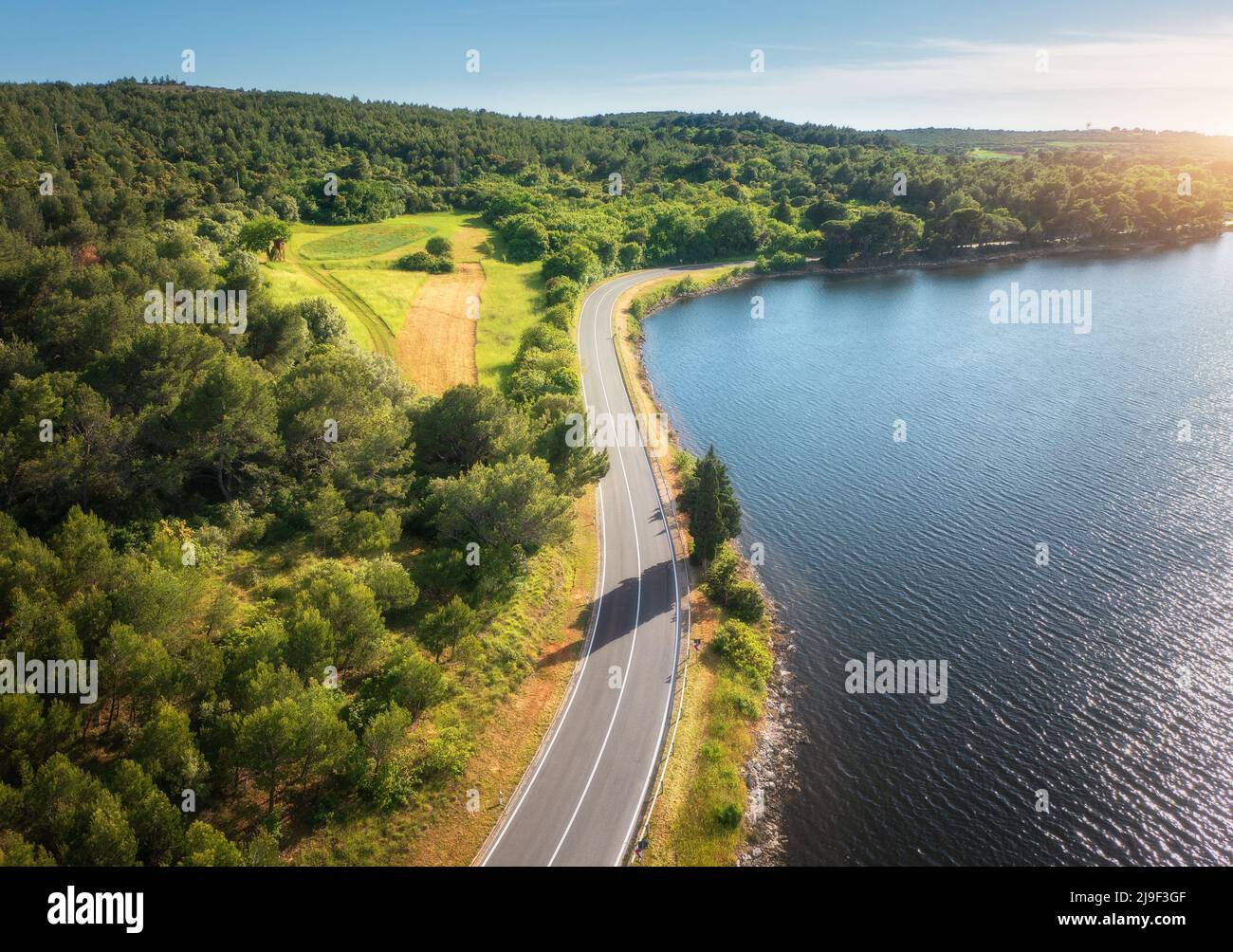 Aerial view of road near blue sea, forest at sunset in summer Stock Photo