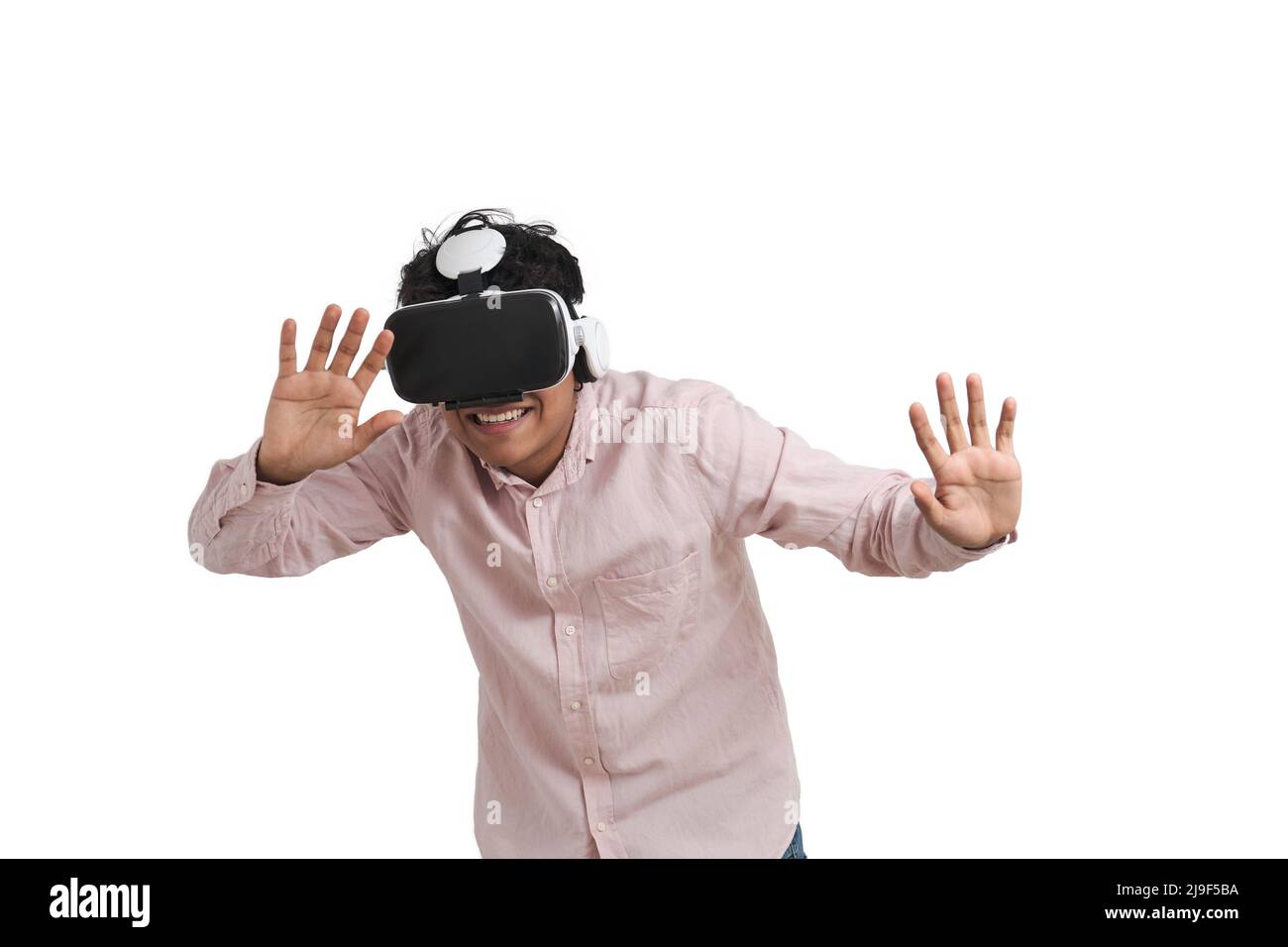 Young peruvian man laughing using virtual reality headset, isolated. Stock Photo