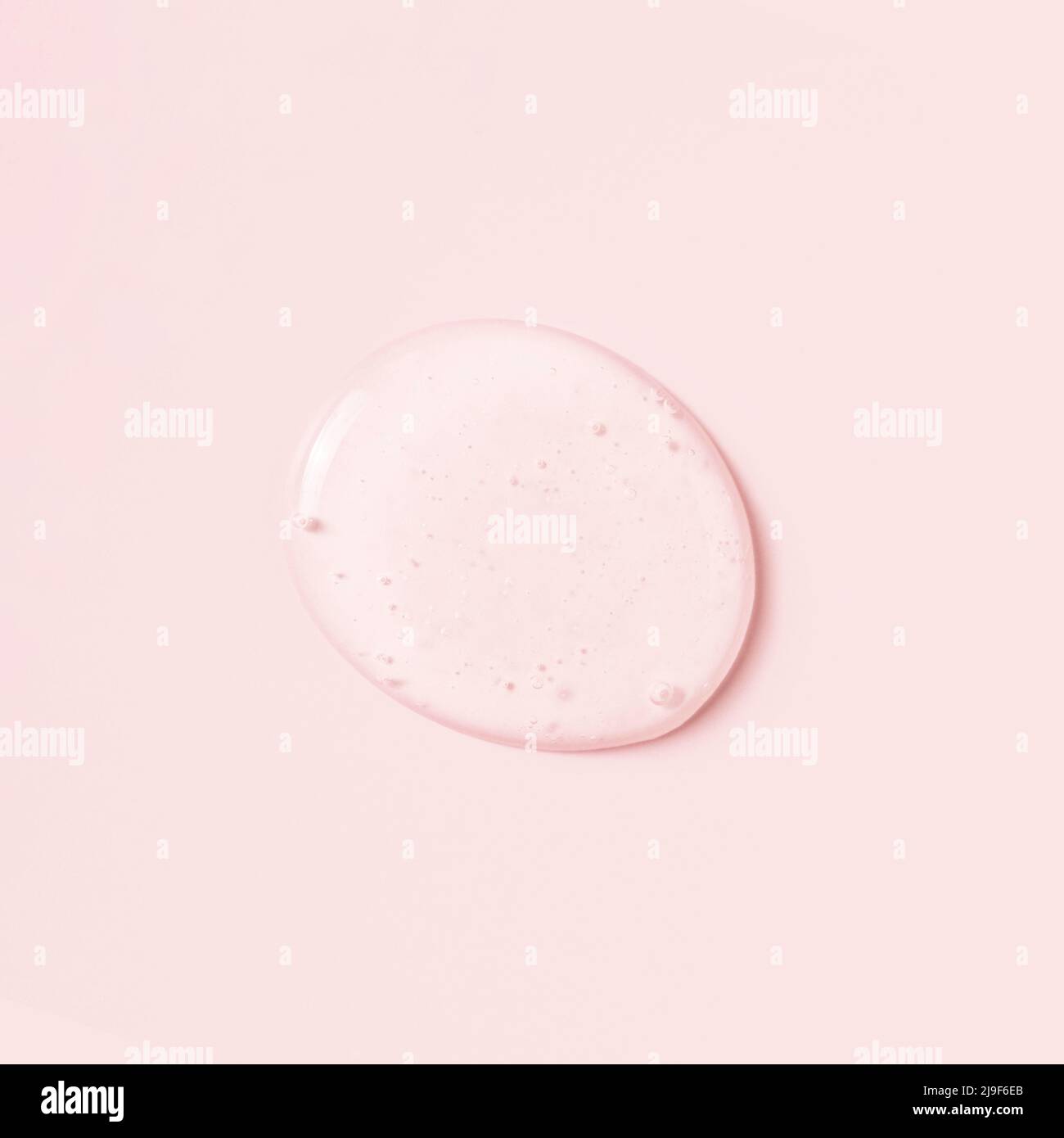 Drop of cosmetic liquid or gel on pink background. Stock Photo