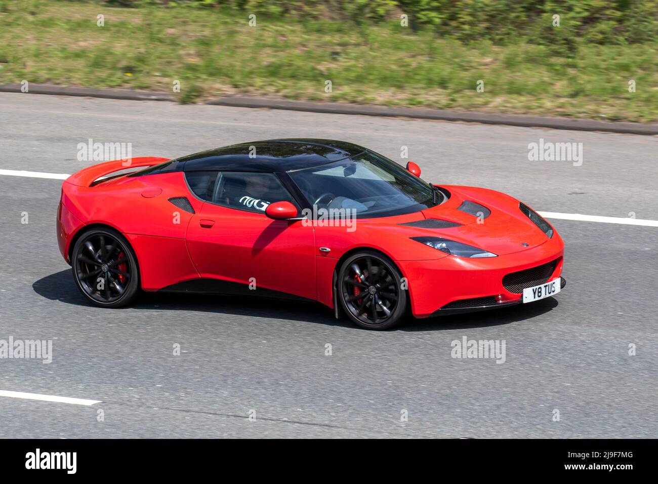2013 red Lotus Evora Sports Racer 4 V6 3456cc petrol roadster 2dr coupe, 345bhp supercharged sports coupe driving on the M61 Motorway, Manchester, UK Stock Photo