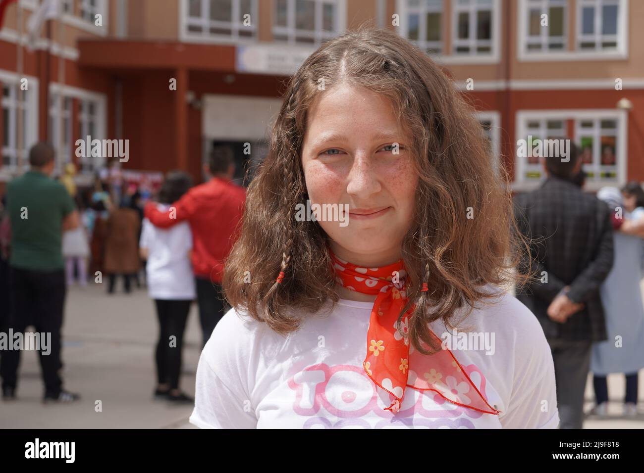 school student girl in white shirt with blue eyes wearing red scarf Stock Photo
