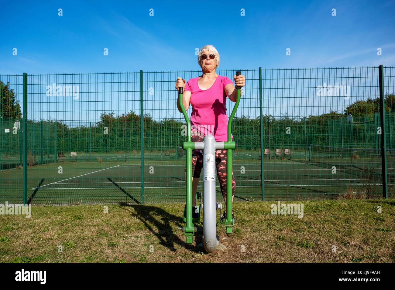 Elderly woman using a free to use Caloo cross rider exercise machine Stock Photo