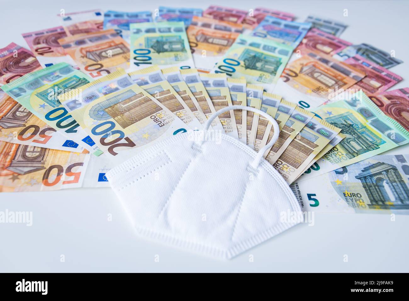 Corona face mask with a bundle of Euro banknotes Stock Photo