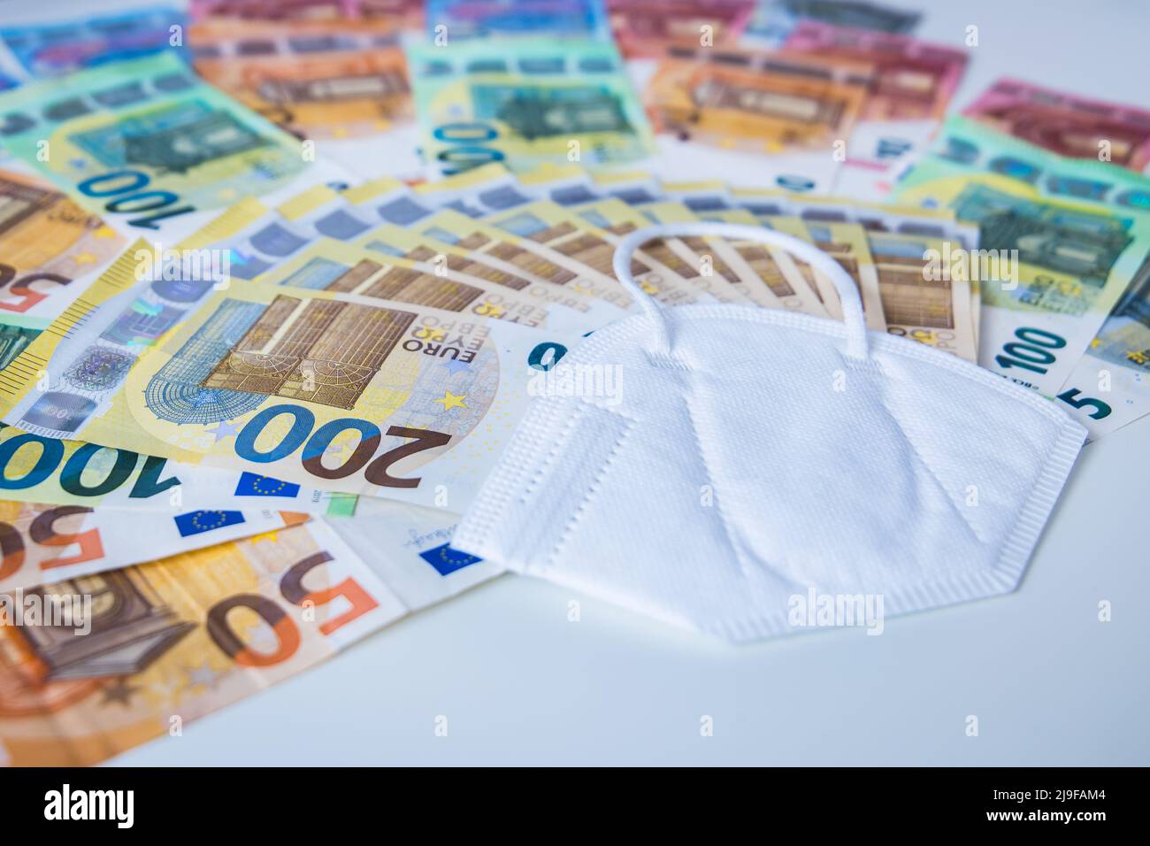 Corona face mask with a bundle of Euro banknotes Stock Photo