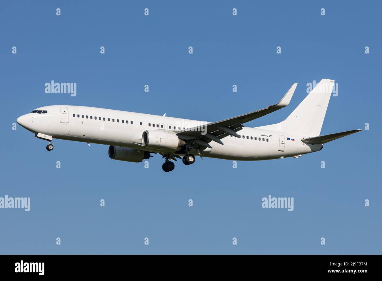 Full white neutralized airliner Boeing 737-800 of slovakian Carrier Air Explore landing at an airport in front of clear blue sky Stock Photo