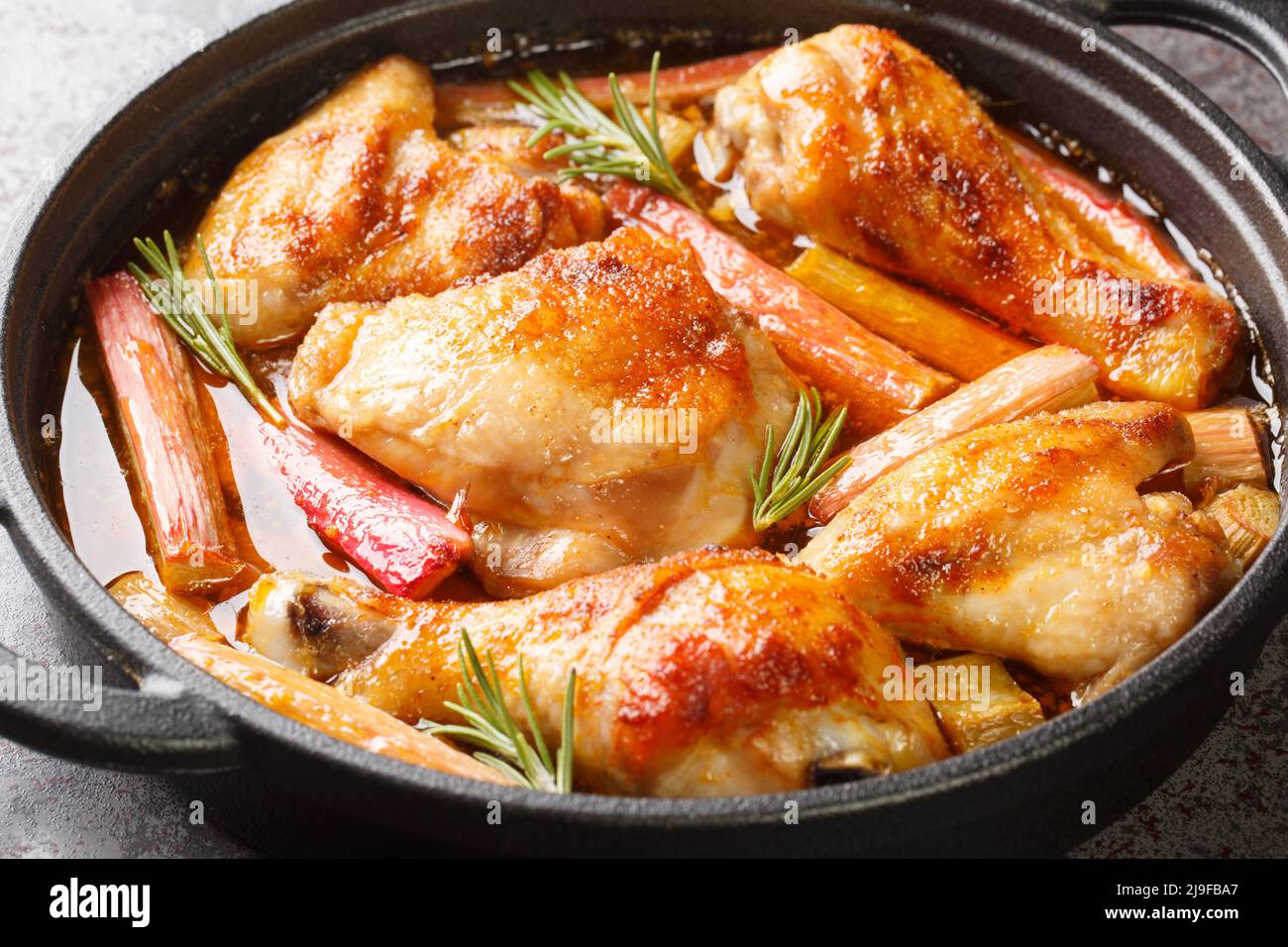 Chicken stew with rhubarb, rosemary and white wine close-up in a frying pan on the table. horizontal Stock Photo