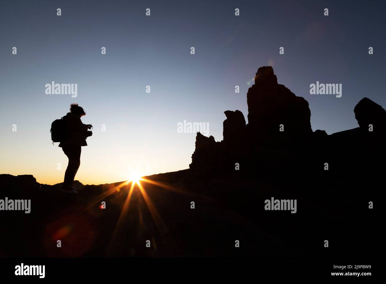 A person filming the sunset in Teide National Park in Tenerife, Spain. The park is the location of Mount Teide, Stock Photo