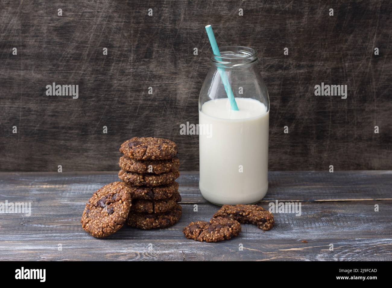 Healthy gluten-free buckwheat cookies with chocolate and bottle of milk on a wooden table Stock Photo