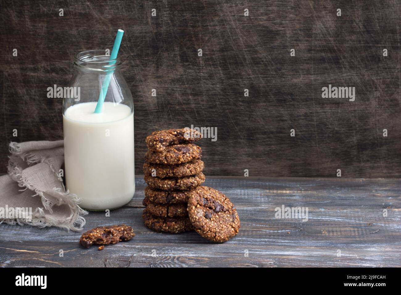 Healthy gluten-free buckwheat cookies with chocolate and bottle of milk on a wooden table, space Stock Photo