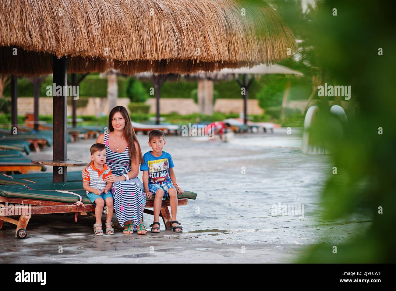 Mother with two sons sitting on sunbed near pool at egyptian resort