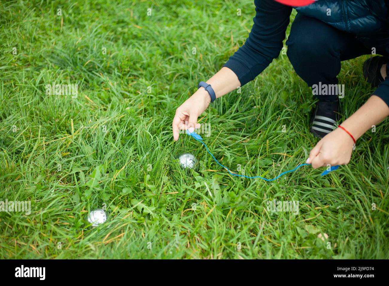 Playing on green grass. Game of steel balls. Sports competition for points. Girls measure accuracy of projectile. Stock Photo