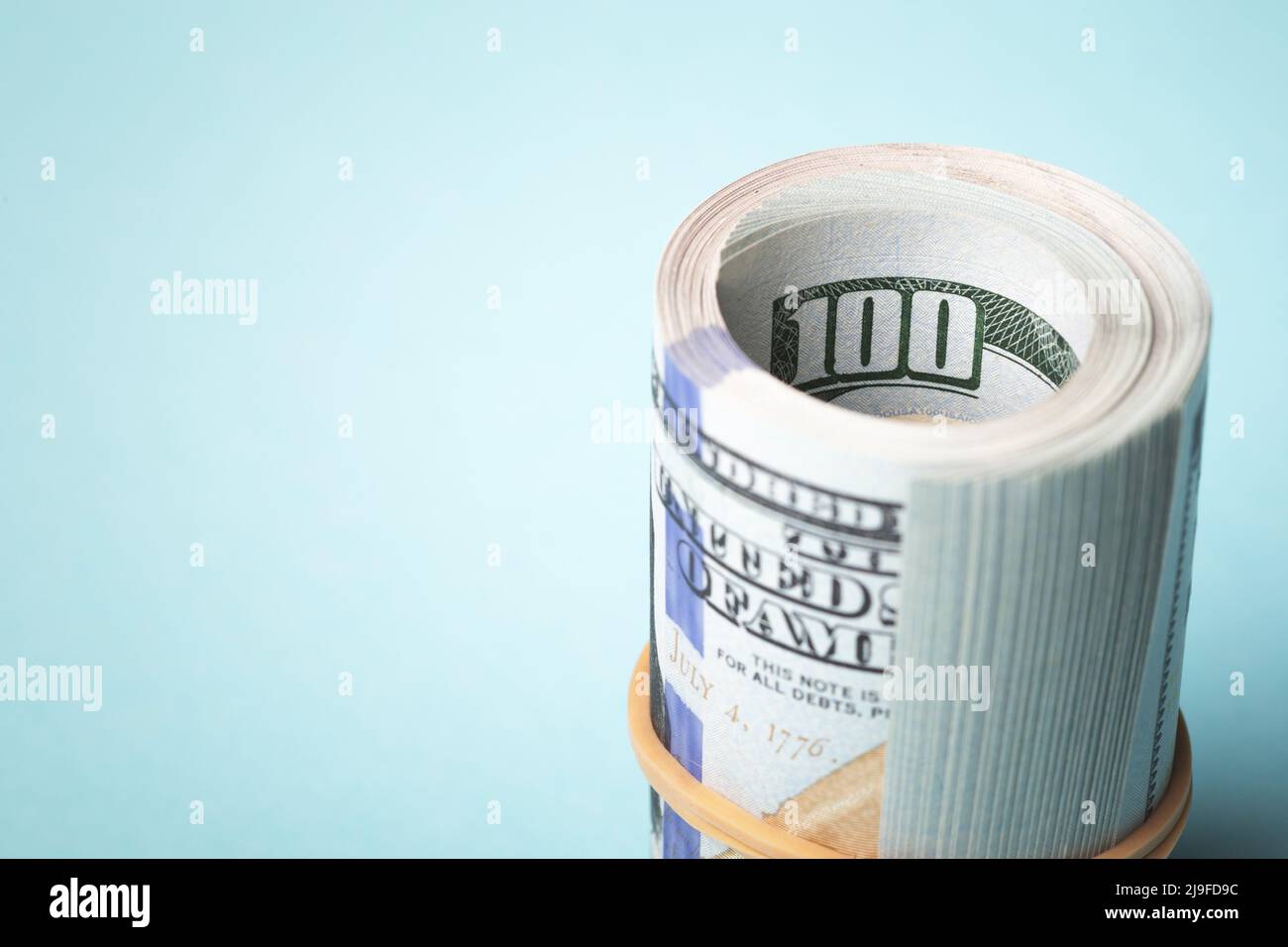 Roll of one hundred american dollars on blue background. Stock Photo