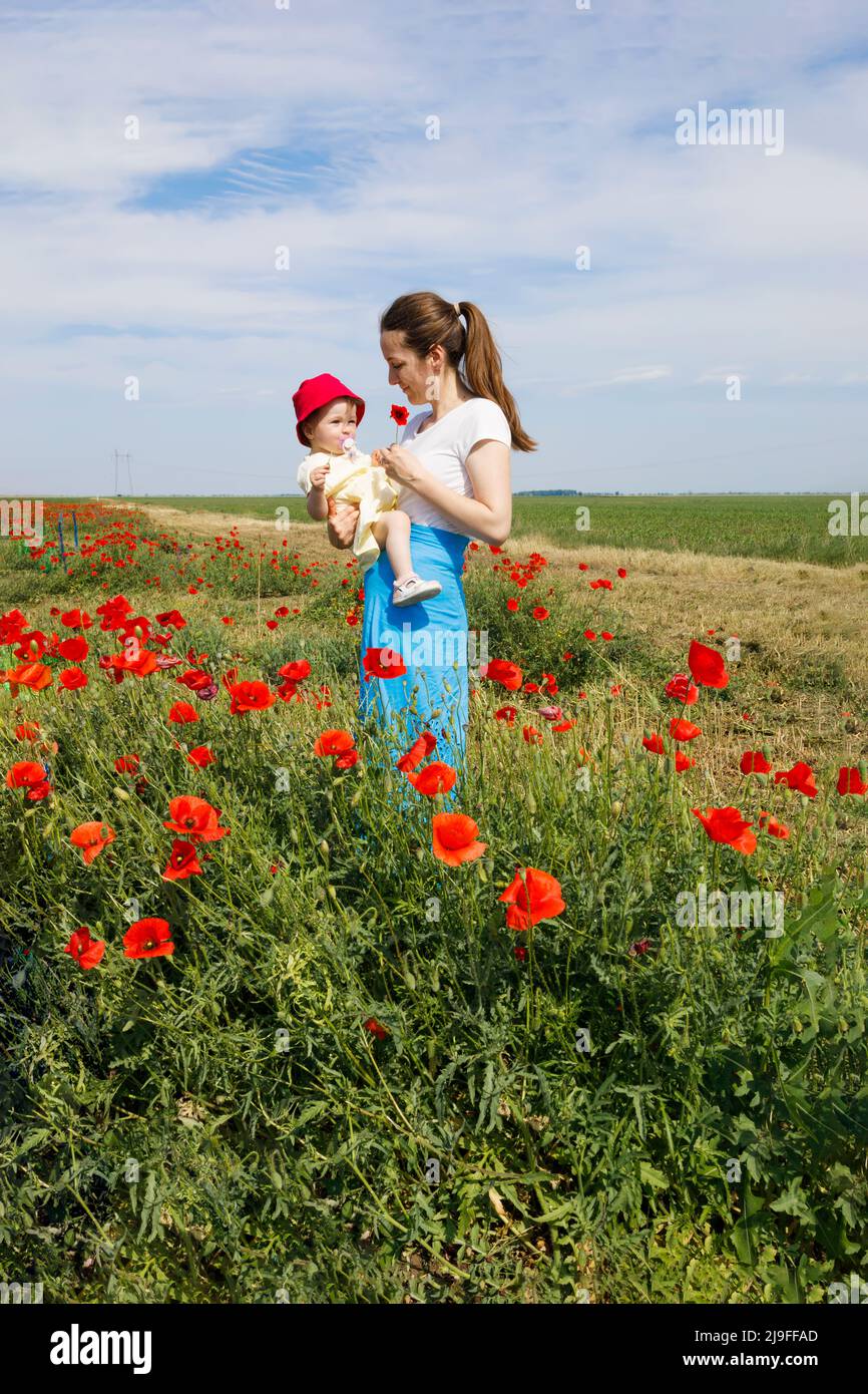 A mother showing a poppy flower to her daughter Stock Photo