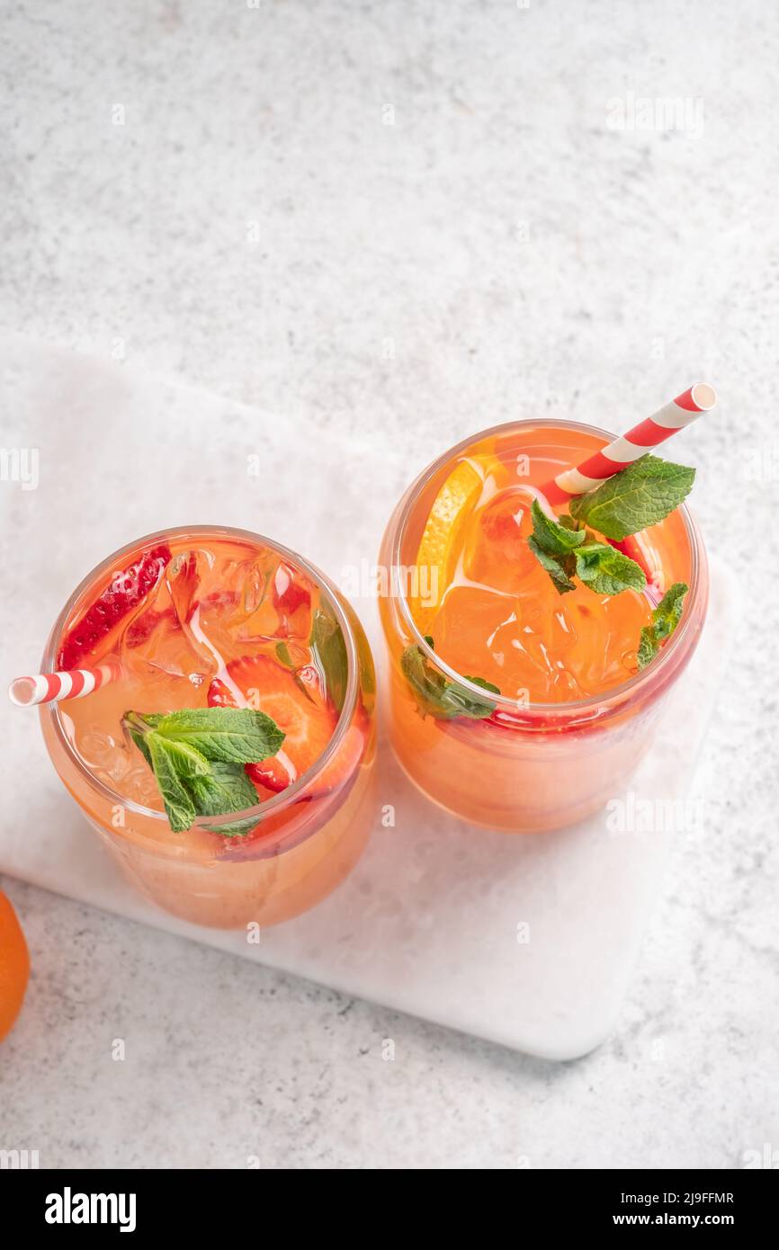 Delicious Orange lemonade with strawberries on grey table, space for text. Fresh summer cocktail Stock Photo