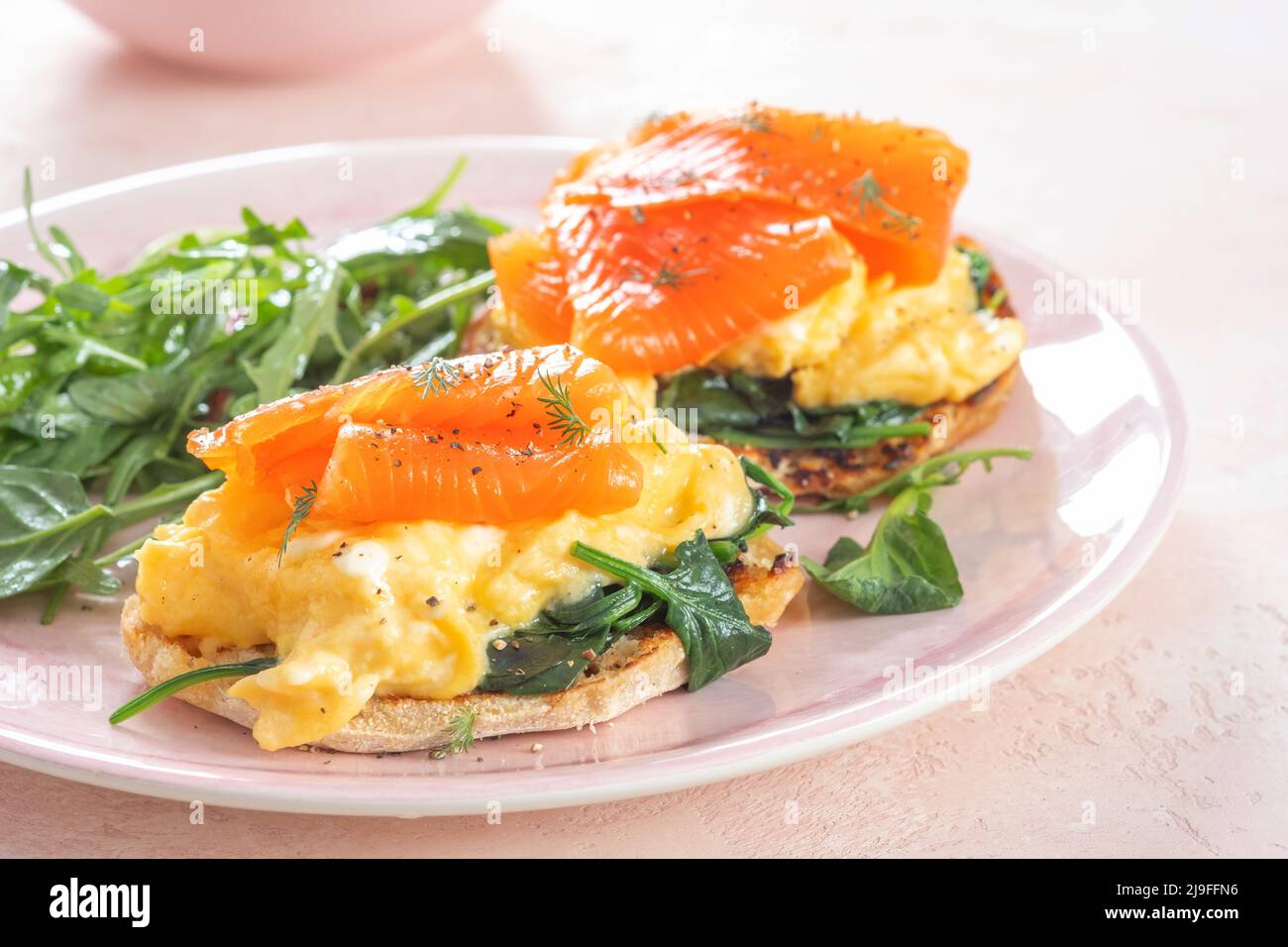 Smoked salmon with scrambled eggs and spinach on a toasted English muffin. Stock Photo